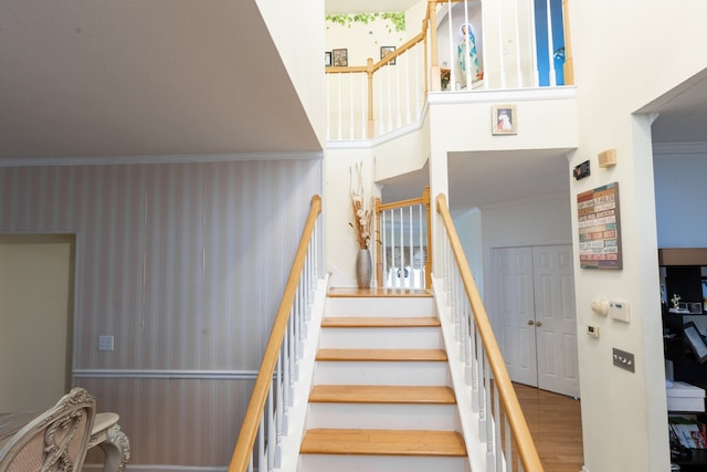 stairway with hardwood / wood-style floors and crown molding