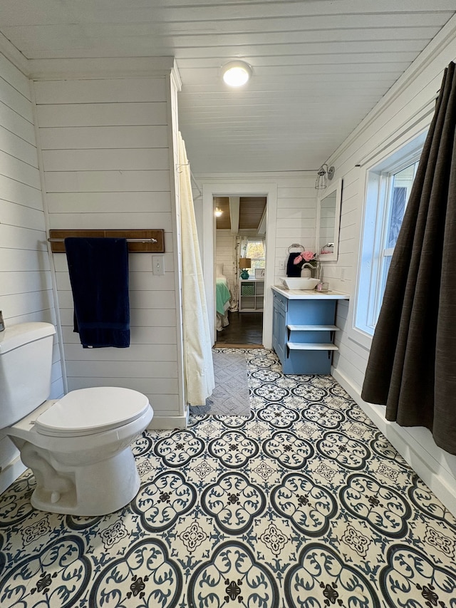 bathroom featuring tile patterned flooring, wooden walls, and toilet