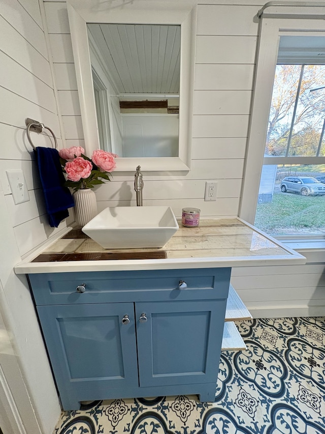 bathroom with tile patterned flooring, vanity, and wood walls