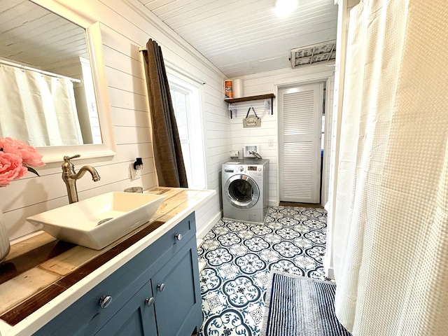 laundry room featuring wooden walls, washer / clothes dryer, and sink