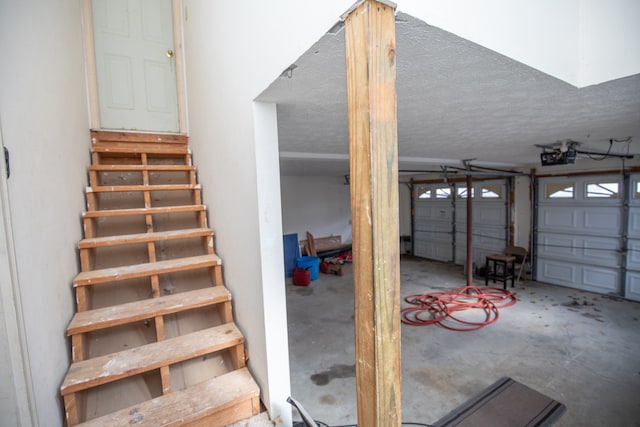 staircase with a textured ceiling and concrete floors