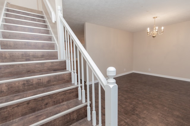 stairs featuring wood-type flooring, a textured ceiling, and a chandelier