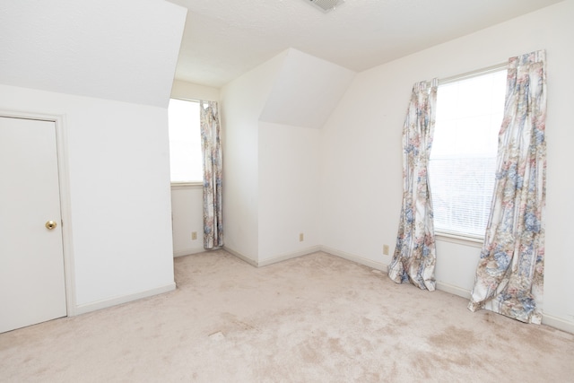 bonus room with light colored carpet, plenty of natural light, and lofted ceiling