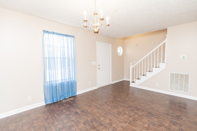 foyer entrance featuring dark hardwood / wood-style flooring, a textured ceiling, and a notable chandelier