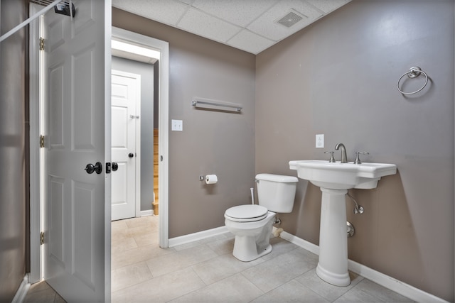 bathroom with toilet, tile patterned floors, and a drop ceiling