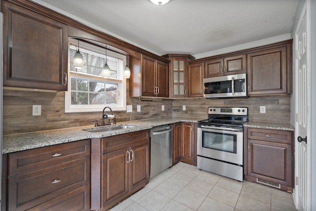 kitchen featuring light stone countertops, sink, decorative backsplash, light tile patterned floors, and appliances with stainless steel finishes