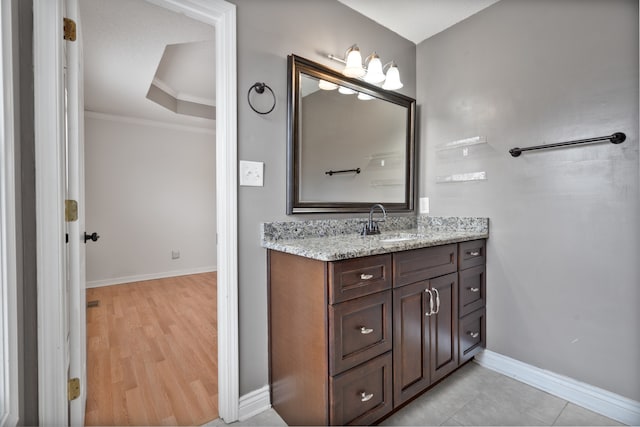 bathroom featuring a tray ceiling, vanity, ornamental molding, and hardwood / wood-style flooring