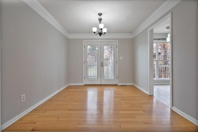 unfurnished dining area featuring french doors, ornamental molding, a notable chandelier, and light wood-type flooring