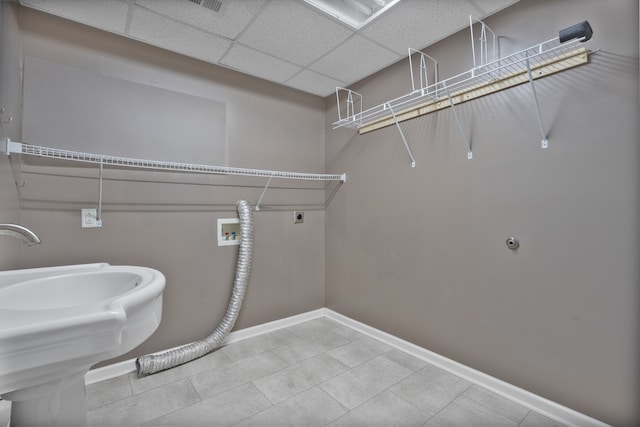 clothes washing area with hookup for an electric dryer, sink, tile patterned floors, and hookup for a washing machine