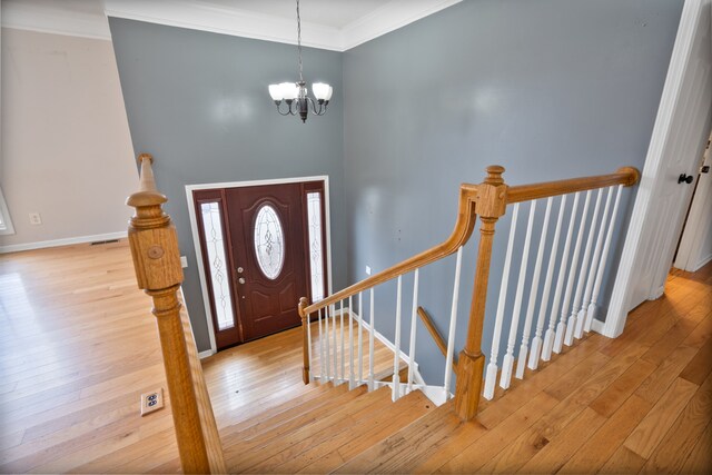 foyer entrance featuring crown molding, a notable chandelier, and light wood-type flooring