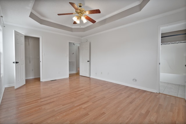 unfurnished bedroom featuring a tray ceiling, light hardwood / wood-style flooring, ceiling fan, and ornamental molding