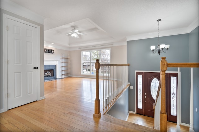 foyer featuring ceiling fan with notable chandelier, crown molding, and light hardwood / wood-style flooring