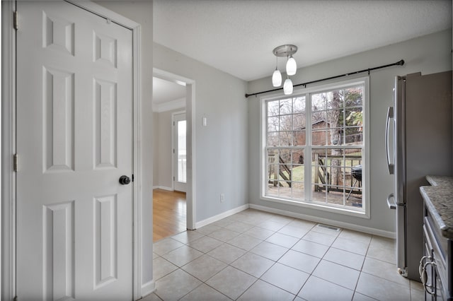 unfurnished dining area with light tile patterned floors and a textured ceiling