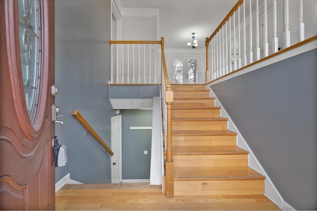 staircase with hardwood / wood-style floors, a notable chandelier, and crown molding