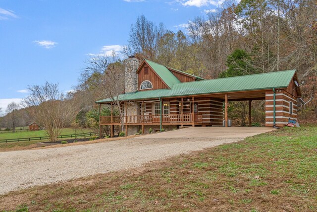 1055 Wades Branch Rd, Centerville, TN 37033 - log home with dirt driveway, a porch, a chimney, an attached carport, and metal roof