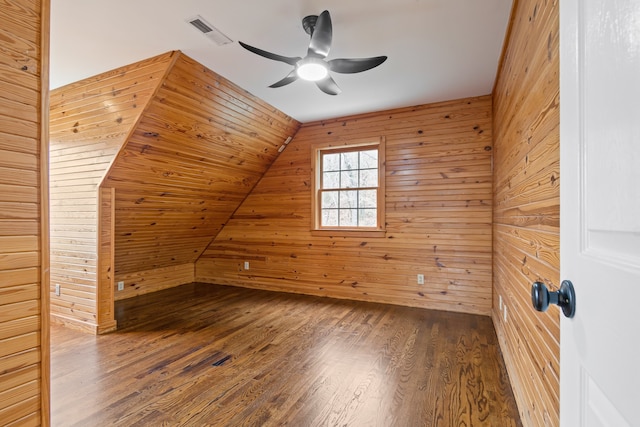 additional living space with hardwood / wood-style floors, vaulted ceiling, ceiling fan, and wooden walls