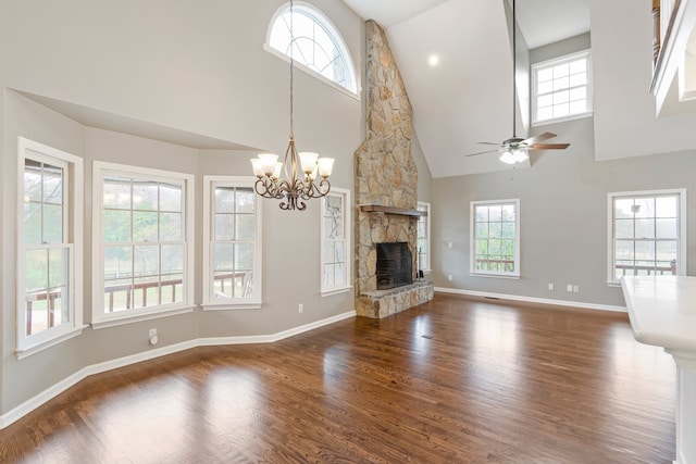 unfurnished living room featuring a fireplace, dark hardwood / wood-style flooring, high vaulted ceiling, and ceiling fan with notable chandelier