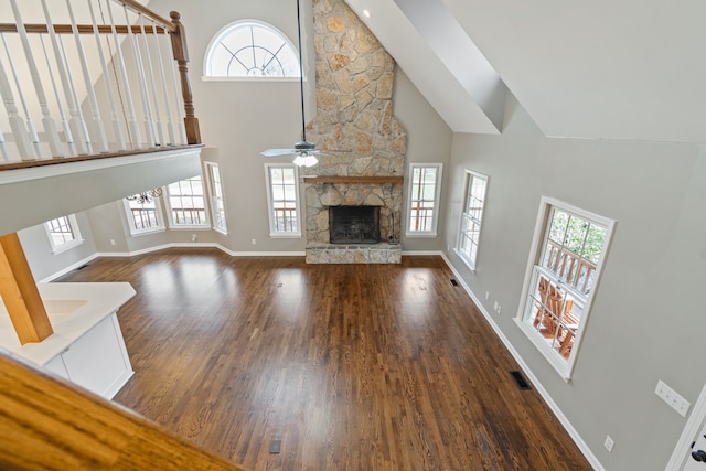 unfurnished living room with dark hardwood / wood-style floors, high vaulted ceiling, ceiling fan, and a stone fireplace