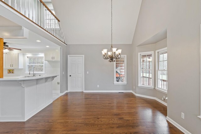 1055 Wades Branch Rd, Centerville, TN 37033 - unfurnished dining area featuring a sink, a ceiling fan, a chandelier, high vaulted ceiling, and dark wood-style floors