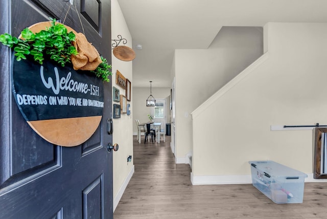 entryway featuring a barn door, hardwood / wood-style flooring, and a notable chandelier