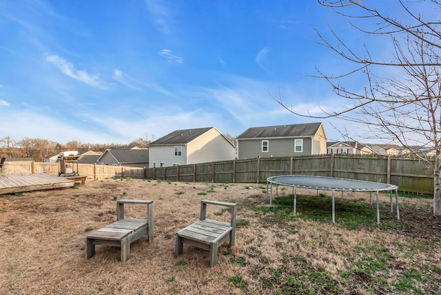 view of yard with a trampoline and a deck