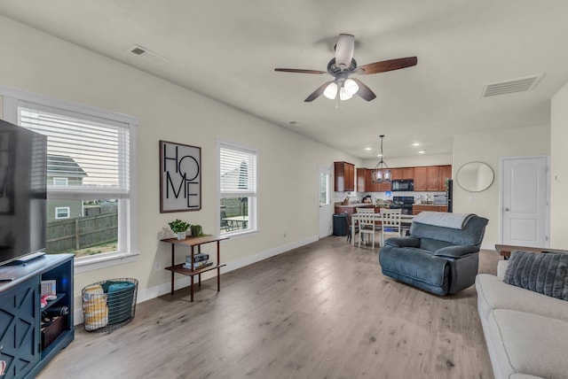 living room featuring ceiling fan, a healthy amount of sunlight, and light wood-type flooring