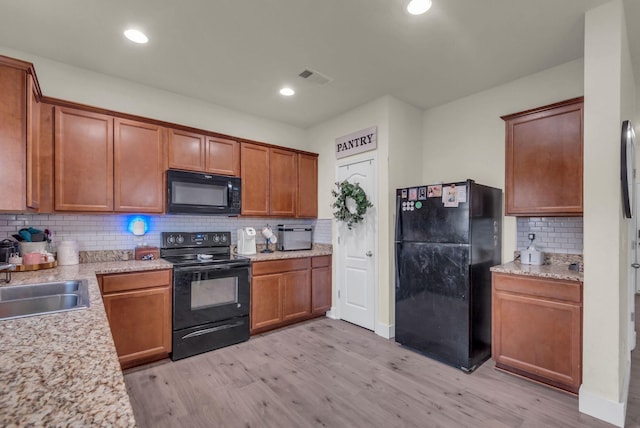 kitchen featuring black appliances, decorative backsplash, sink, and light hardwood / wood-style flooring