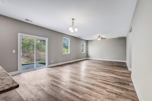 interior space featuring plenty of natural light, ceiling fan with notable chandelier, and hardwood / wood-style flooring