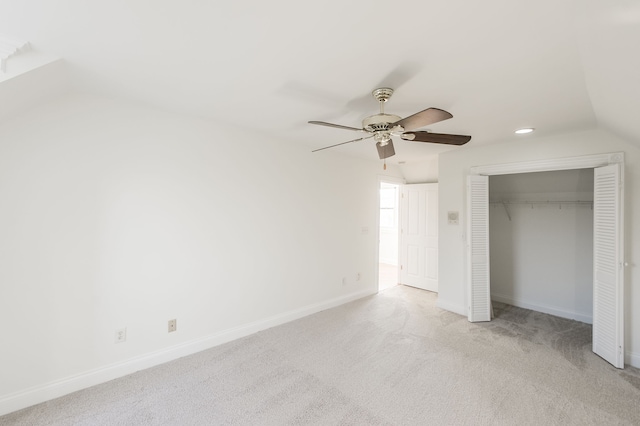 unfurnished bedroom featuring light carpet, a closet, ceiling fan, and lofted ceiling