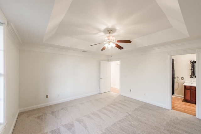 carpeted empty room featuring ceiling fan, a raised ceiling, and crown molding