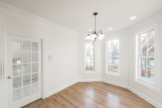 unfurnished dining area featuring a chandelier, light hardwood / wood-style floors, and ornamental molding