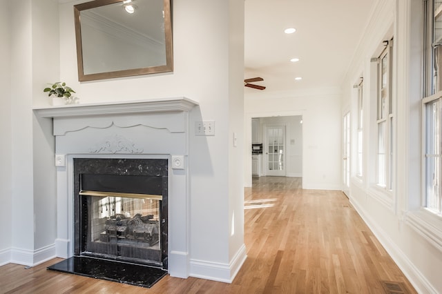 hallway featuring plenty of natural light, ornamental molding, and light wood-type flooring