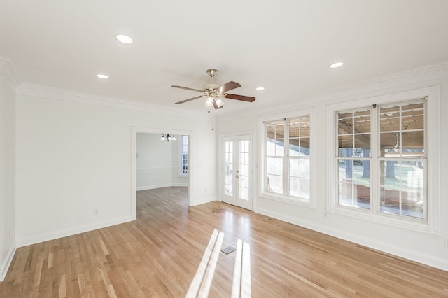 unfurnished room featuring ceiling fan with notable chandelier, light wood-type flooring, and crown molding