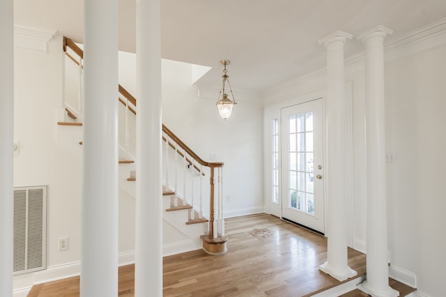 foyer featuring hardwood / wood-style floors, ornate columns, and ornamental molding