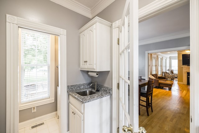 kitchen featuring ornamental molding, sink, stone countertops, light hardwood / wood-style flooring, and white cabinetry