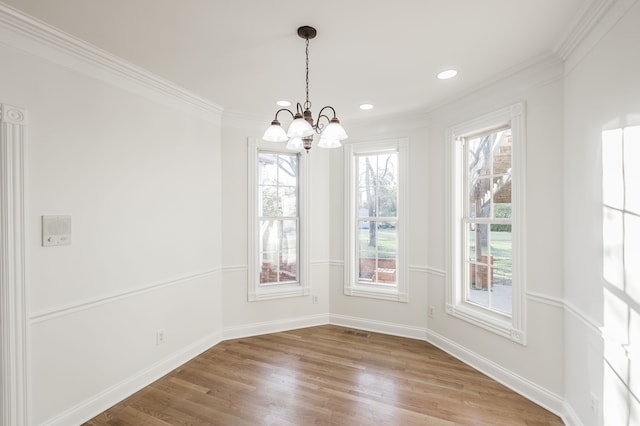 unfurnished dining area featuring crown molding, an inviting chandelier, and hardwood / wood-style flooring