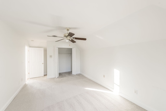 unfurnished bedroom with ceiling fan, a closet, light carpet, and vaulted ceiling