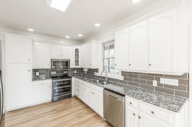 kitchen with white cabinets, crown molding, dark stone countertops, and stainless steel appliances