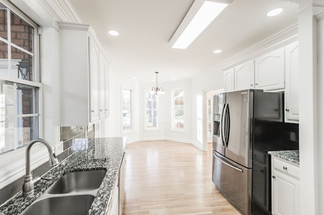 kitchen featuring sink, stainless steel appliances, dark stone countertops, white cabinets, and light wood-type flooring