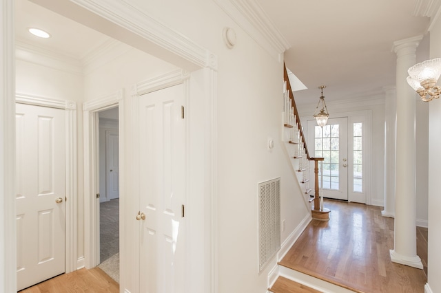 hallway with decorative columns, crown molding, and light hardwood / wood-style flooring