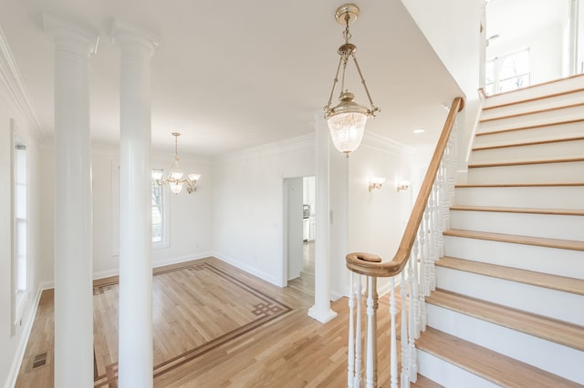 stairway featuring wood-type flooring, an inviting chandelier, and ornamental molding