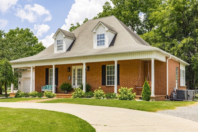 view of front facade featuring covered porch, a garage, cooling unit, and a front yard