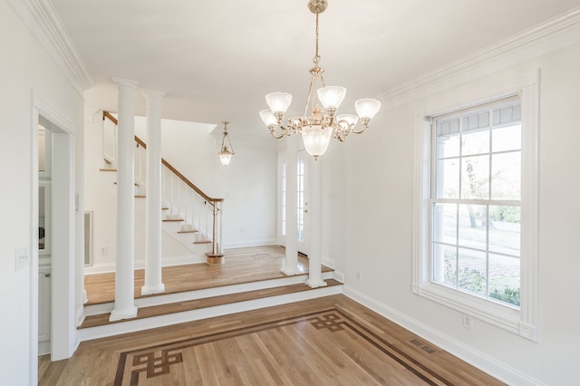 foyer entrance featuring hardwood / wood-style flooring, ornamental molding, a wealth of natural light, and a chandelier