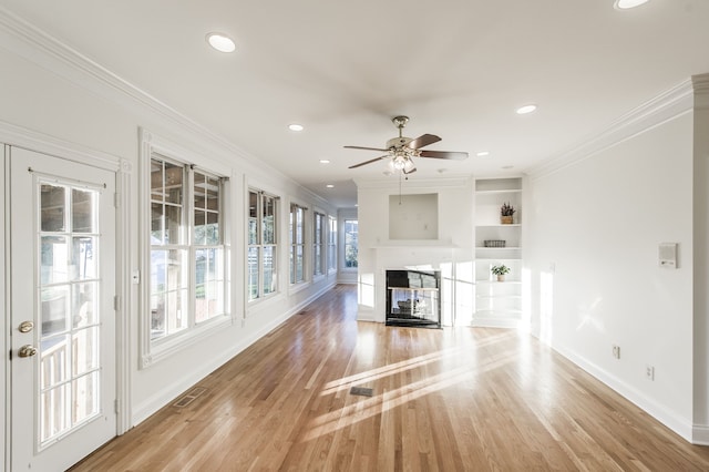 unfurnished living room with ceiling fan, a multi sided fireplace, light wood-type flooring, and crown molding