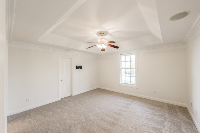 carpeted empty room with a tray ceiling, ceiling fan, and ornamental molding