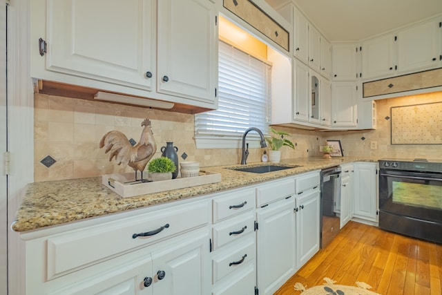 kitchen with white cabinetry, light hardwood / wood-style flooring, black / electric stove, and sink