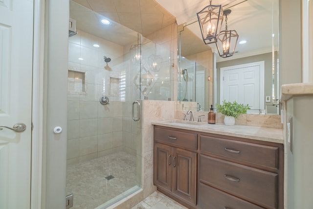 bathroom featuring crown molding, an inviting chandelier, vanity, and walk in shower