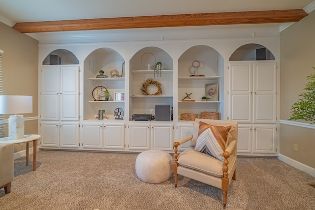 sitting room with built in shelves, light colored carpet, ornamental molding, and beam ceiling