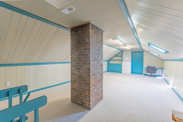 additional living space with light carpet, vaulted ceiling, and wood walls