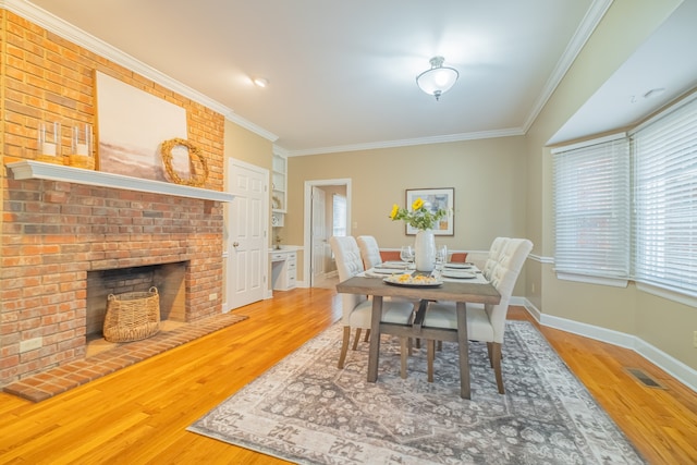 dining space featuring hardwood / wood-style floors, a brick fireplace, and crown molding